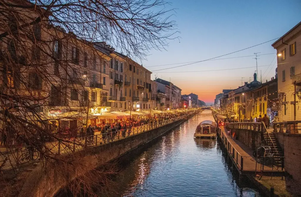 Canal Naviglio Grande al atardecer con terrazas y gente paseando en Milán
